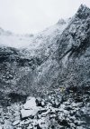 tiny-person-in-yellow-jacket-standing-between-rocks-covered-by-snow-free-photo-1080x1528.jpeg